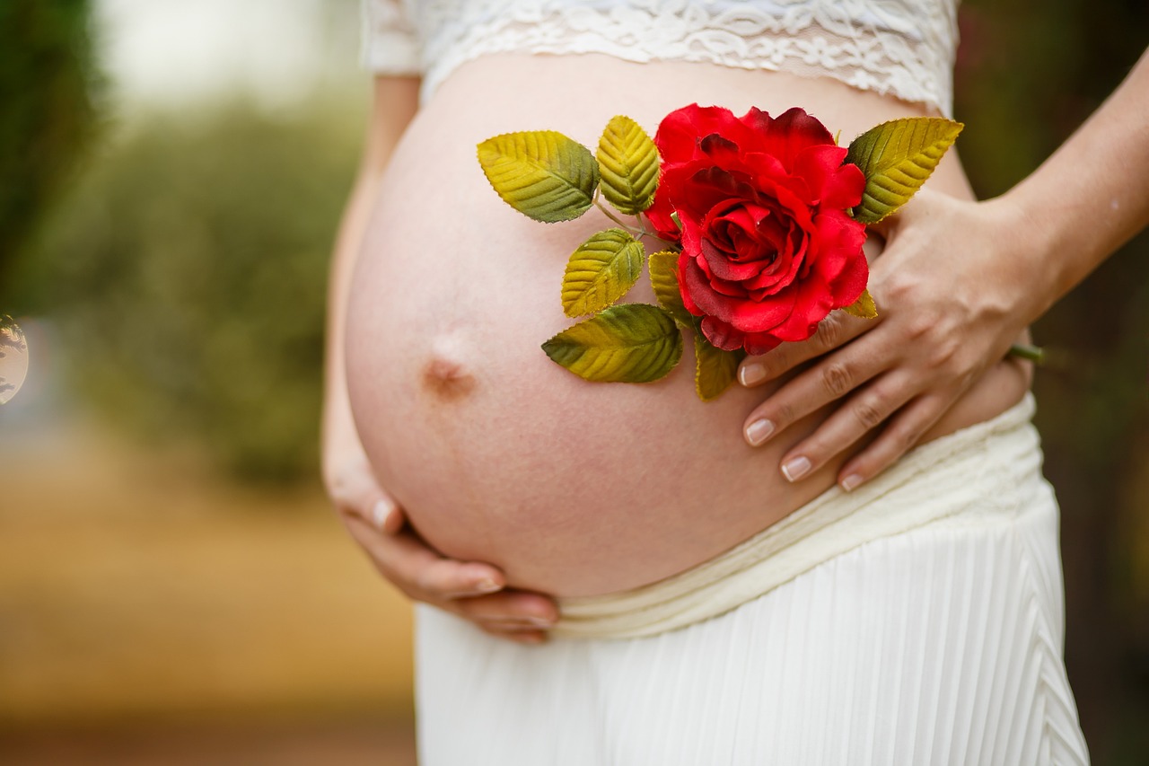 Schwangere Frau hält sich den Bauch und freut sich auf die Geburt