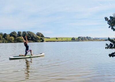 Frau übt Yoga auf dem SUP-Board, Sommer im Ostalbkreis, Bucher Stausee